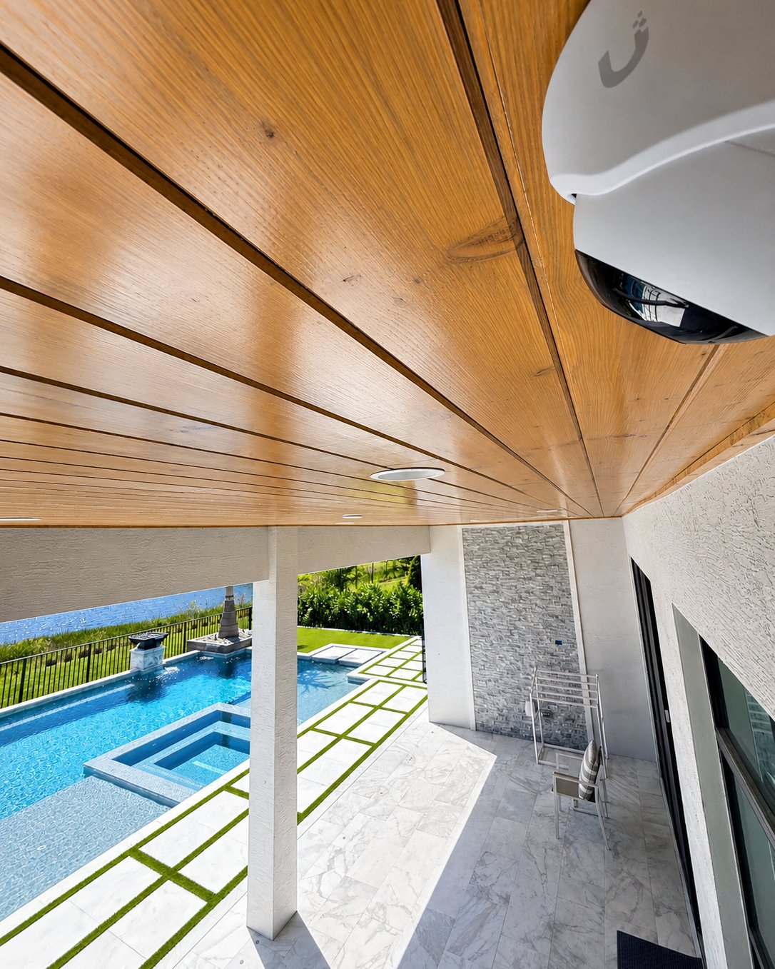 Ubiquiti security camera installed under a modern wood-ceiling patio overlooking a pool in Palm Beach County FL